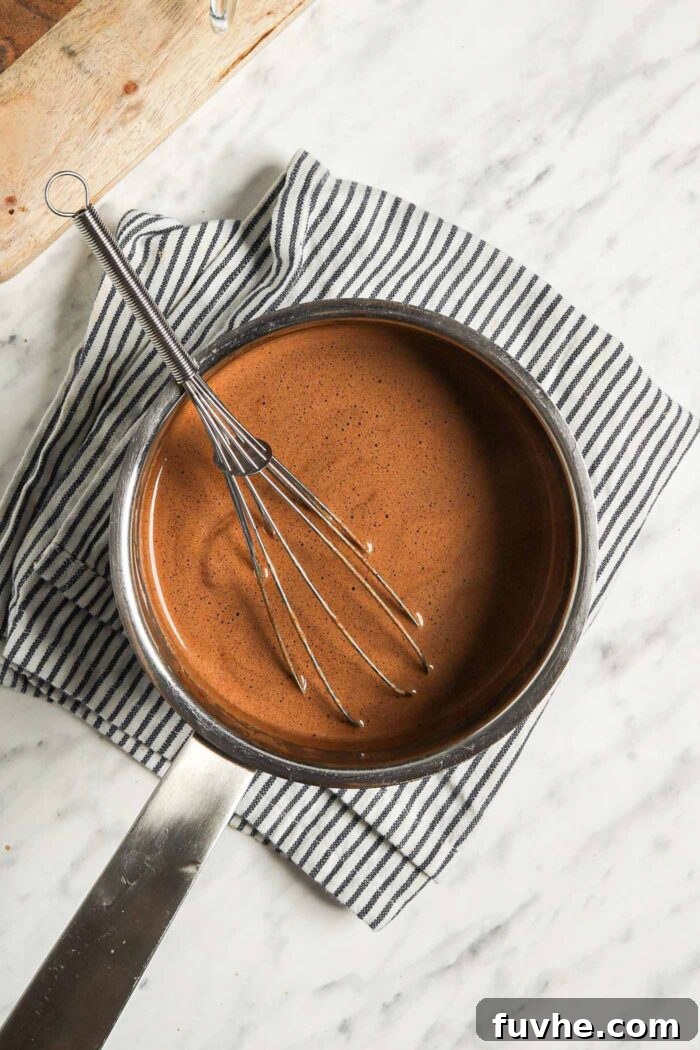Decadent Plant-Based Hot Chocolate 5 Whisk sitting in a small saucepan of hot chocolate.