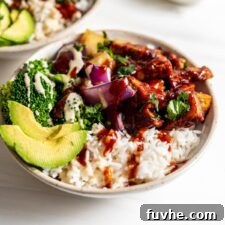 A vibrant dinner bowl featuring rice, savory BBQ tofu, creamy avocado slices, crisp broccoli, sweet pineapple chunks, and tender roasted red onion.