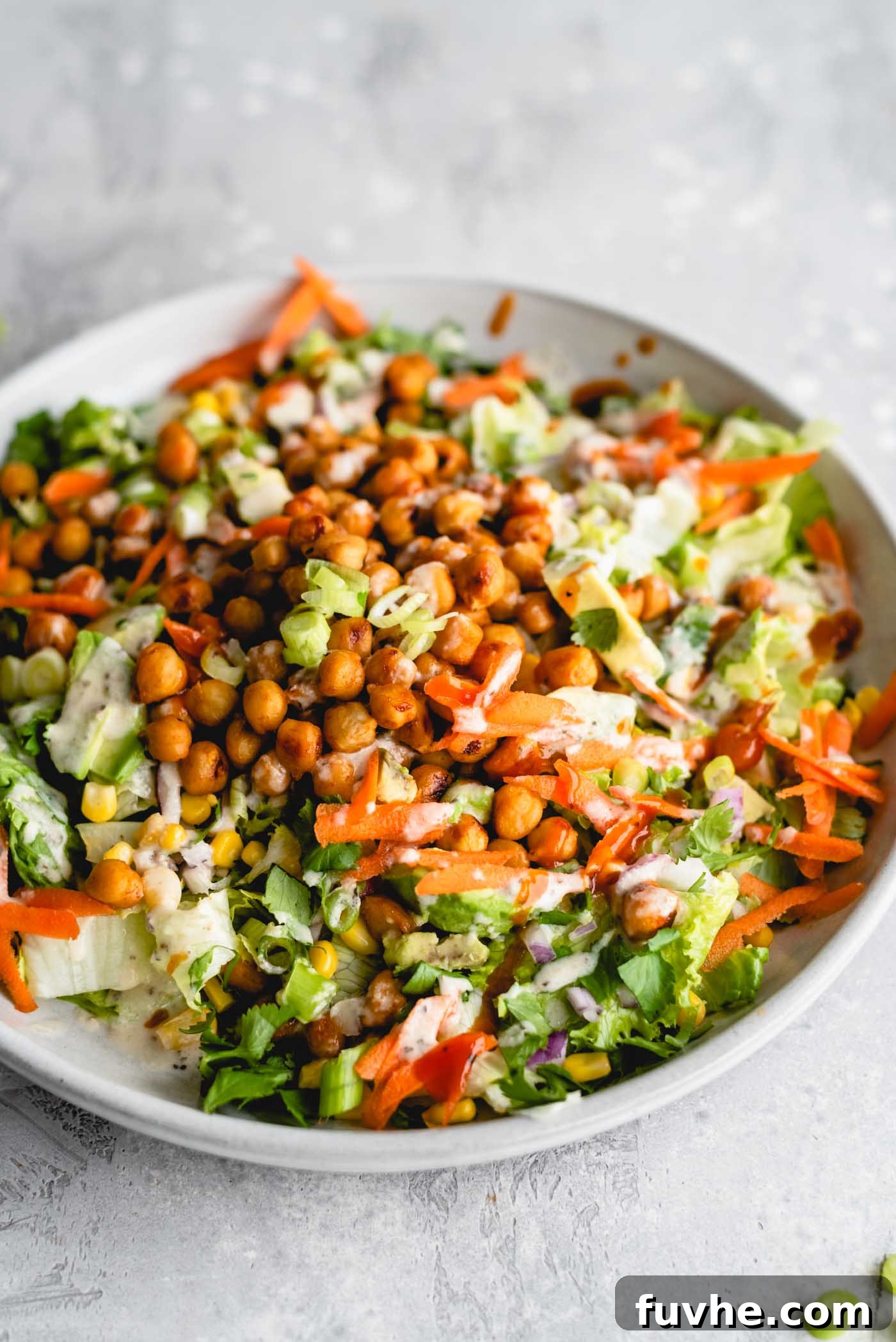 Smoky Vegan BBQ Chickpea Salad 2 BBQ chickpea salad with lettuce, carrot, avocado, corn and tahini ranch dressing on a plate.