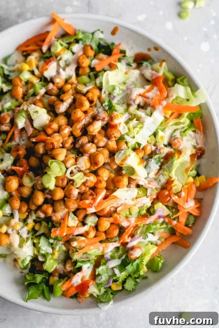 Smoky Vegan BBQ Chickpea Salad 6 Overhead view of a plate of BBQ chickpea salad with tahini sauce, carrot, corn, cilantro, avocado and carrot.