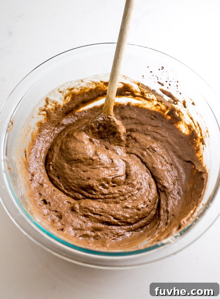 Raw chocolate pancake batter in a glass mixing bowl, showcasing its thick consistency.