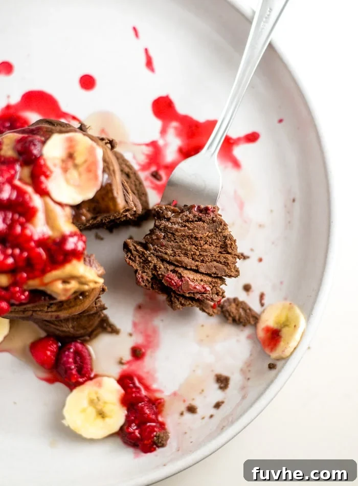 A forkful of decadent chocolate protein pancakes, revealing their fluffy interior.