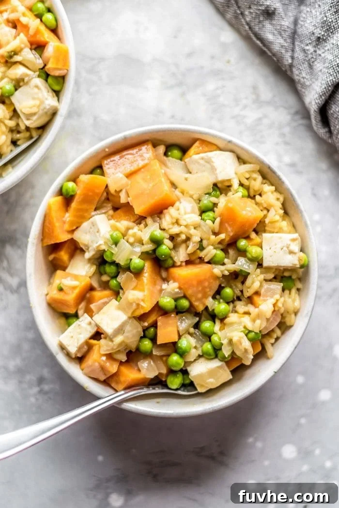Small bowl of sweet potato pea curry with tofu and brown rice.