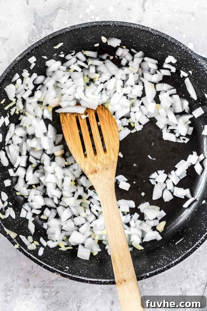 Onions, garlic and ginger being cooked in a skillet.