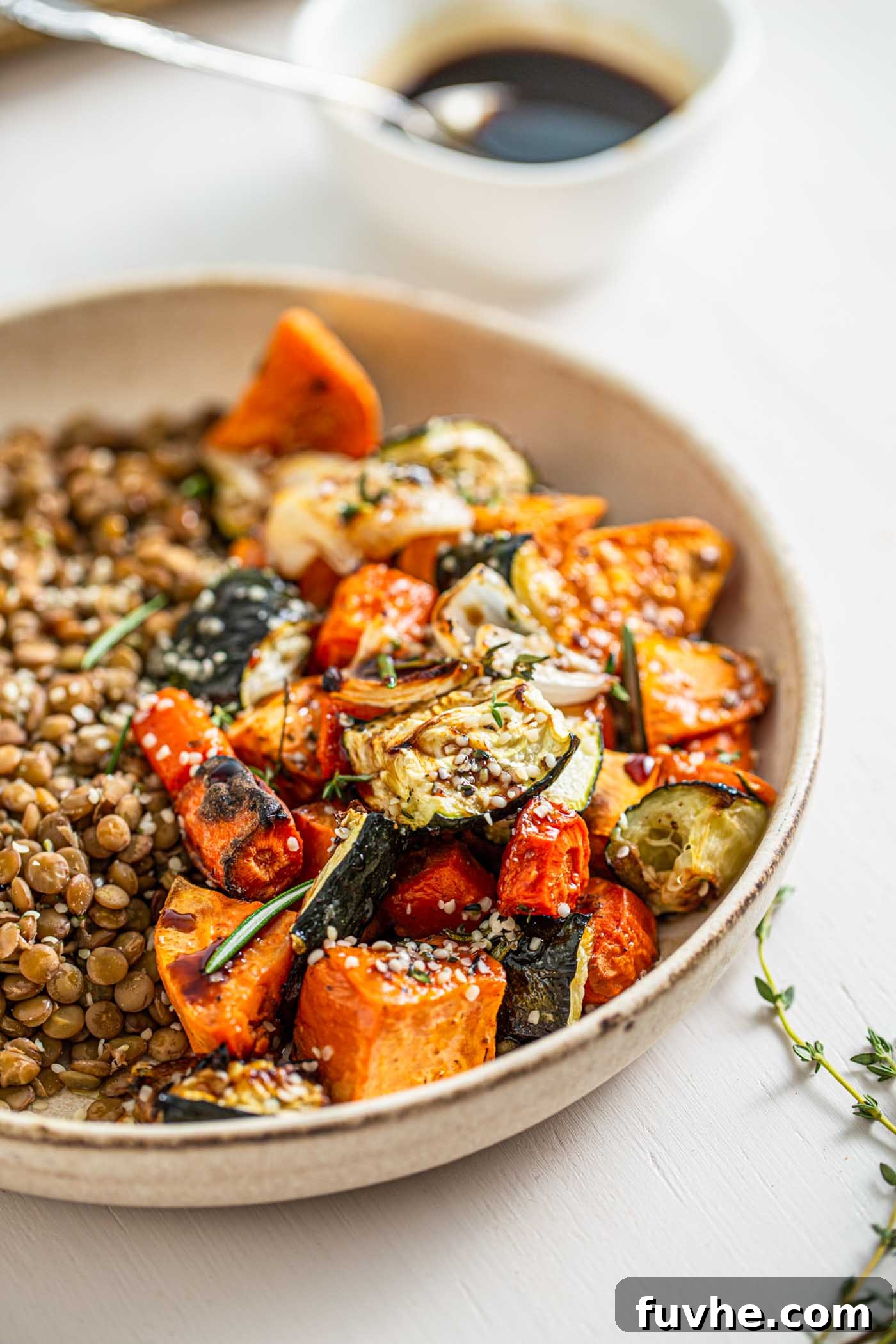 Close up of roasted zucchini, sweet potato and onions with lentils in a bowl, showcasing the rich textures and colors.