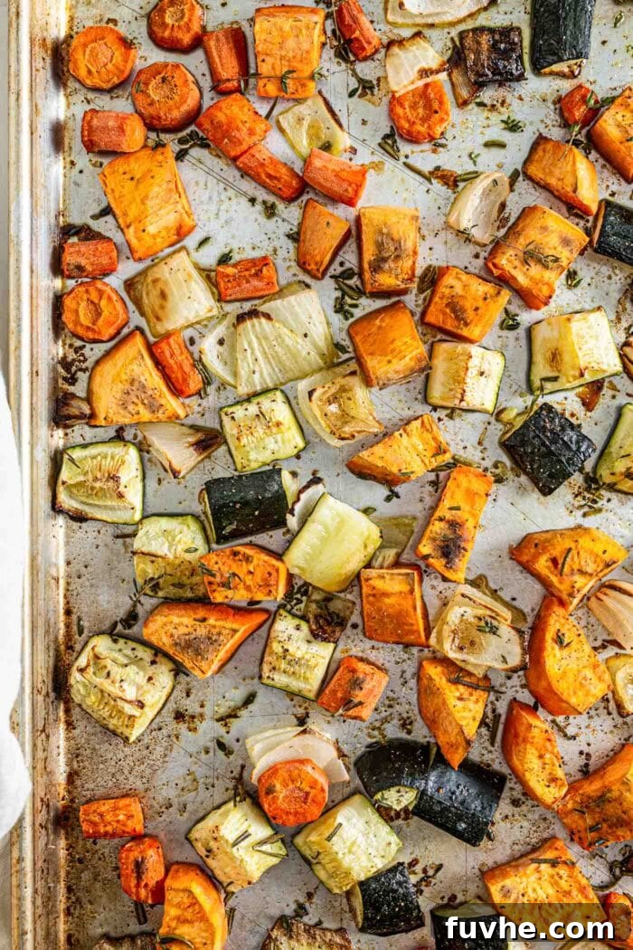 Roasted sweet potato, onion, carrot and zucchini on a baking tray, showing the delicious caramelization.