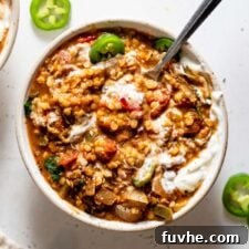 Overhead view of a a bowl of lentil chili with sour cream and jalapeños on top.