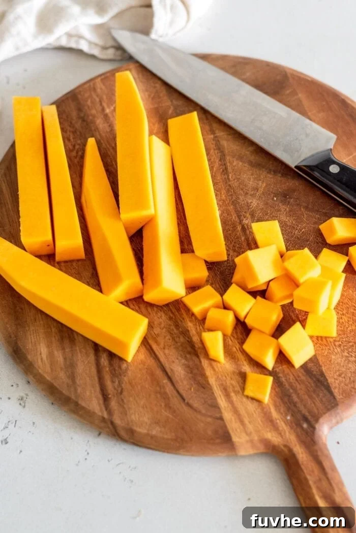 Golden Butternut Lentil Nourishment 3 Peeled butternut squash cut into cubes on a cutting board with a knife, ready for soup.