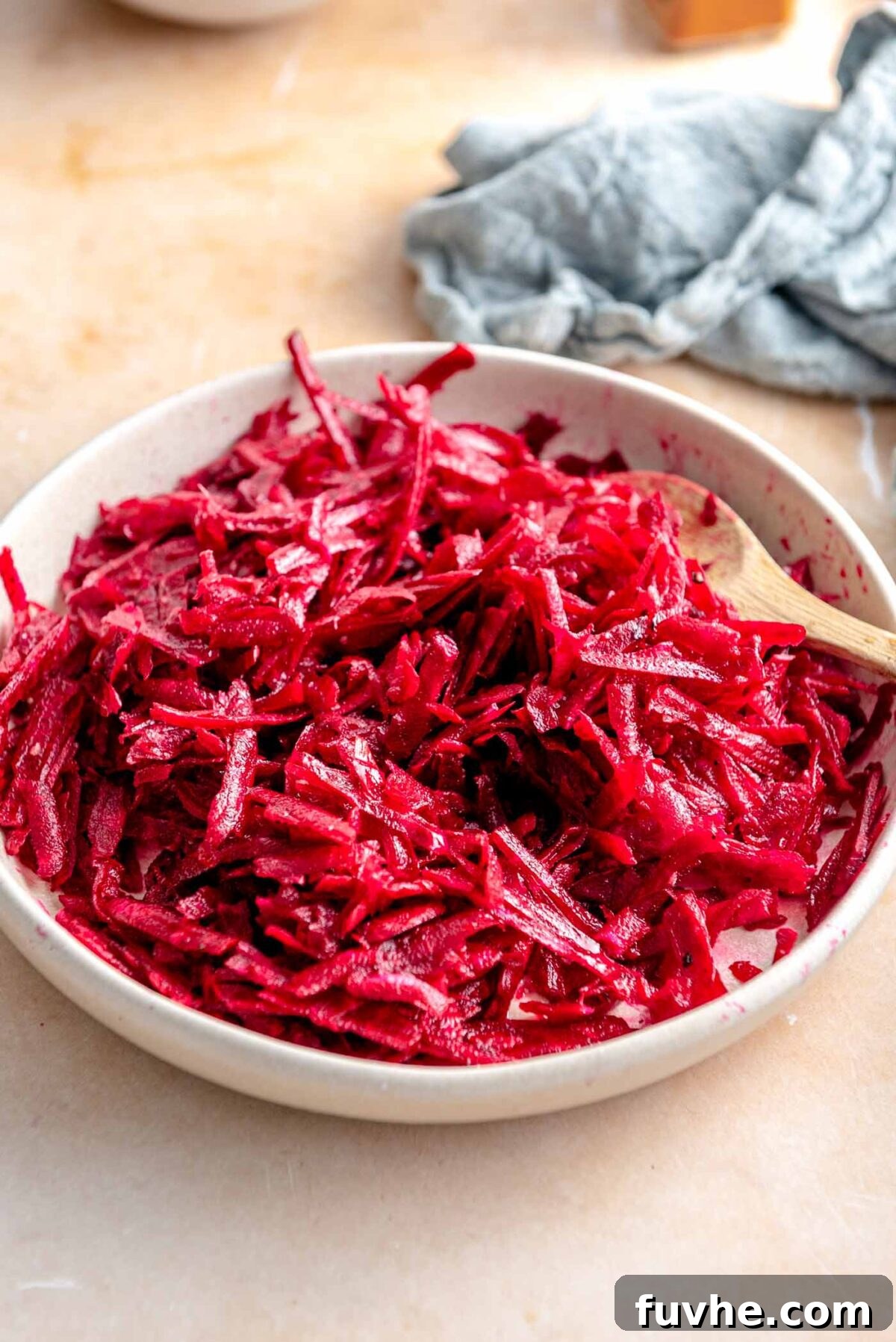 A raw beet, peeled and freshly grated, ready for use in the bowl.