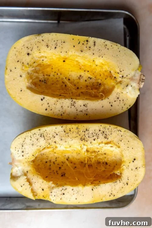Two halves of a spaghetti squash with seeds removed and sprinkled with salt and pepper.