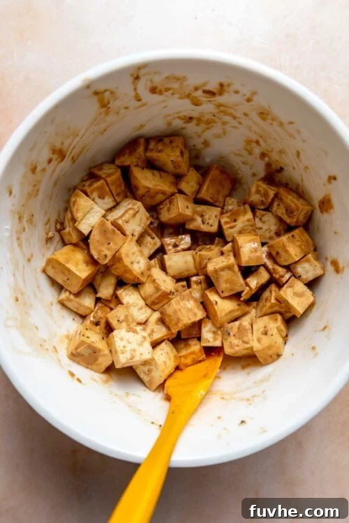 Cubed tofu mixed with soy sauce in a bowl with a small spatula resting in it.