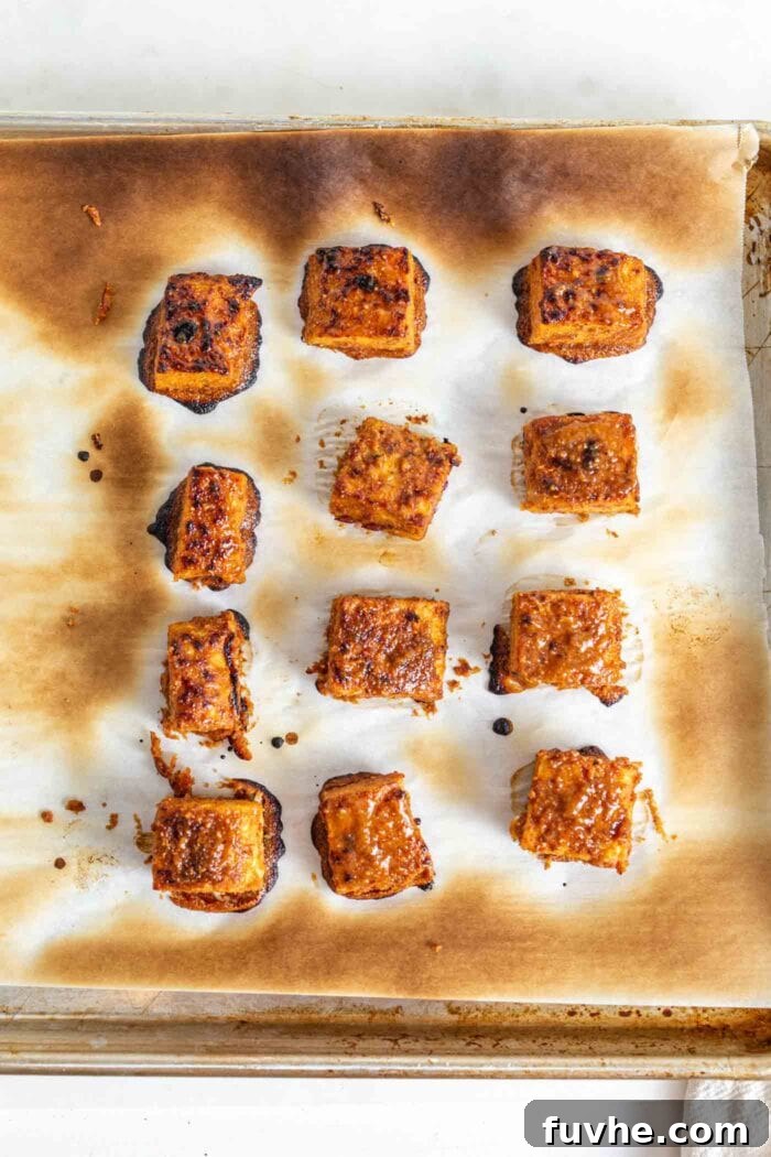 Baked tempeh on a baking tray lined with parchment paper.
