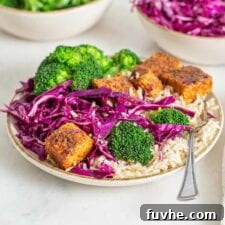 Colourful bowl of brown rice, baked tempeh cubes, broccoli and sliced cabbage.