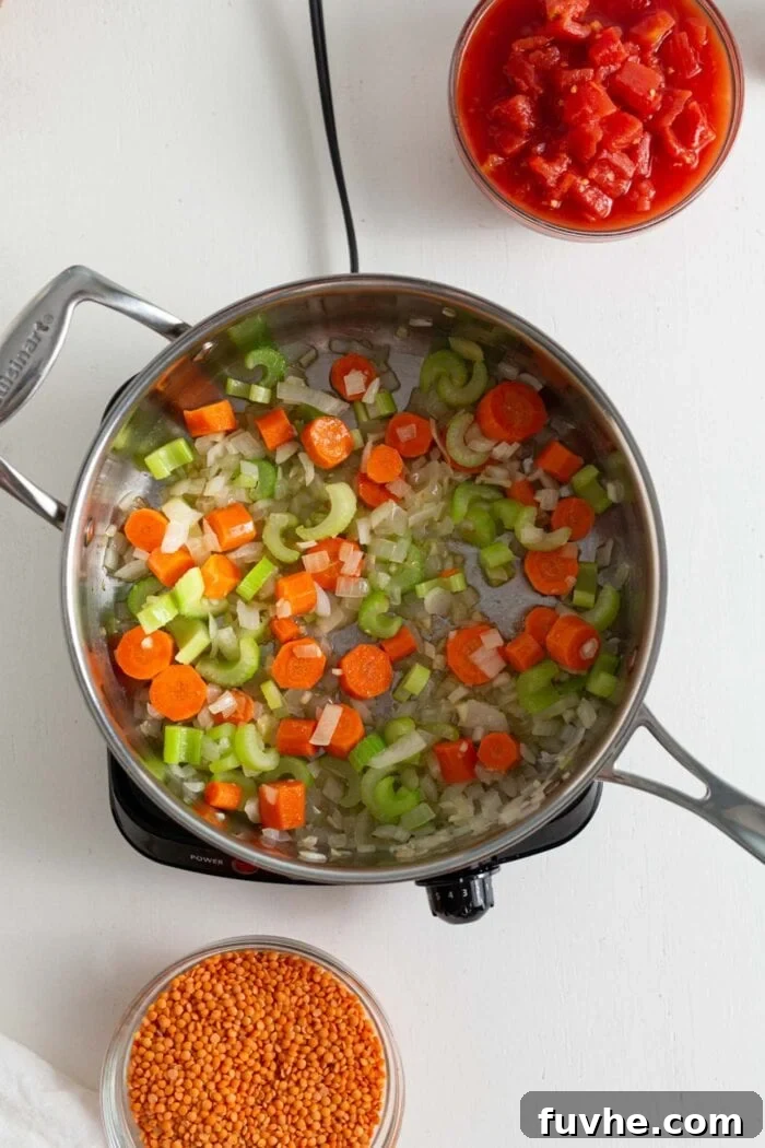 Hearty Curried Lentil Soup 5 The sautéed onion, garlic, carrots, and celery mixed with spices in a skillet.