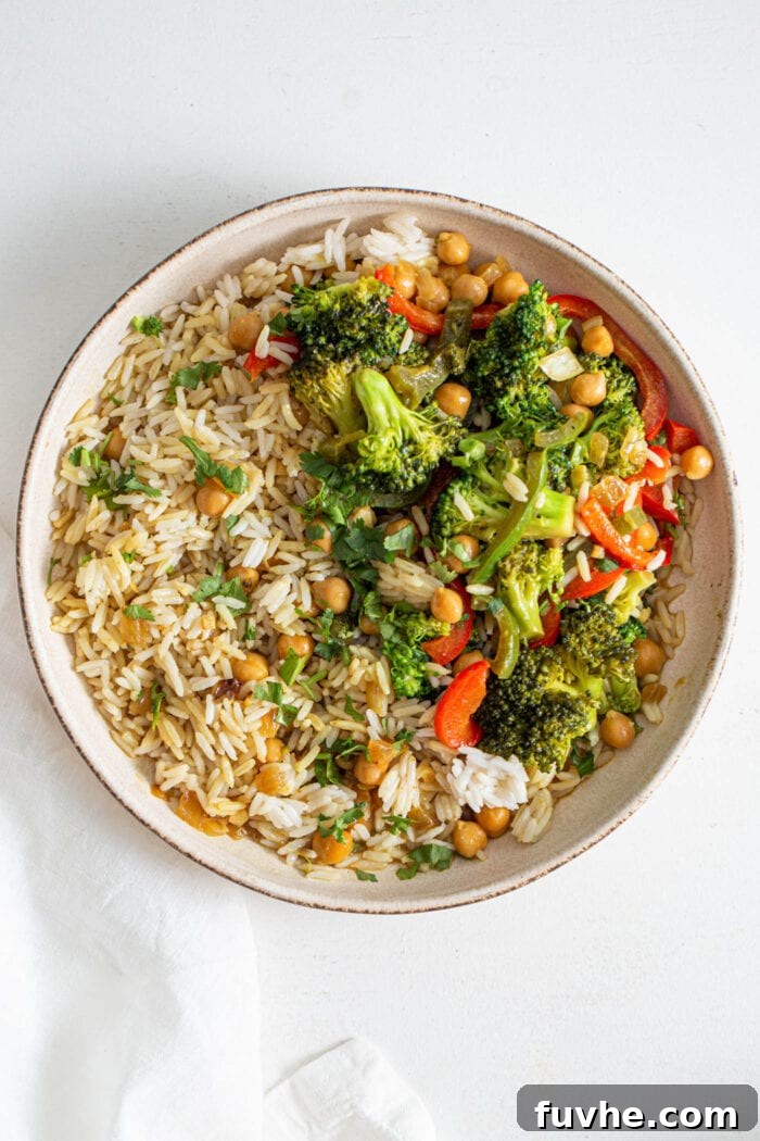 An overhead shot showcasing a hearty bowl of rice topped generously with a vibrant chickpea and vegetable curry, highlighting its appealing textures.