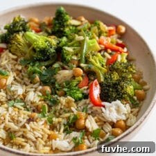 A vibrant bowl of rice, chickpeas, and various vegetables drenched in a rich, creamy curry sauce, ready to be enjoyed.