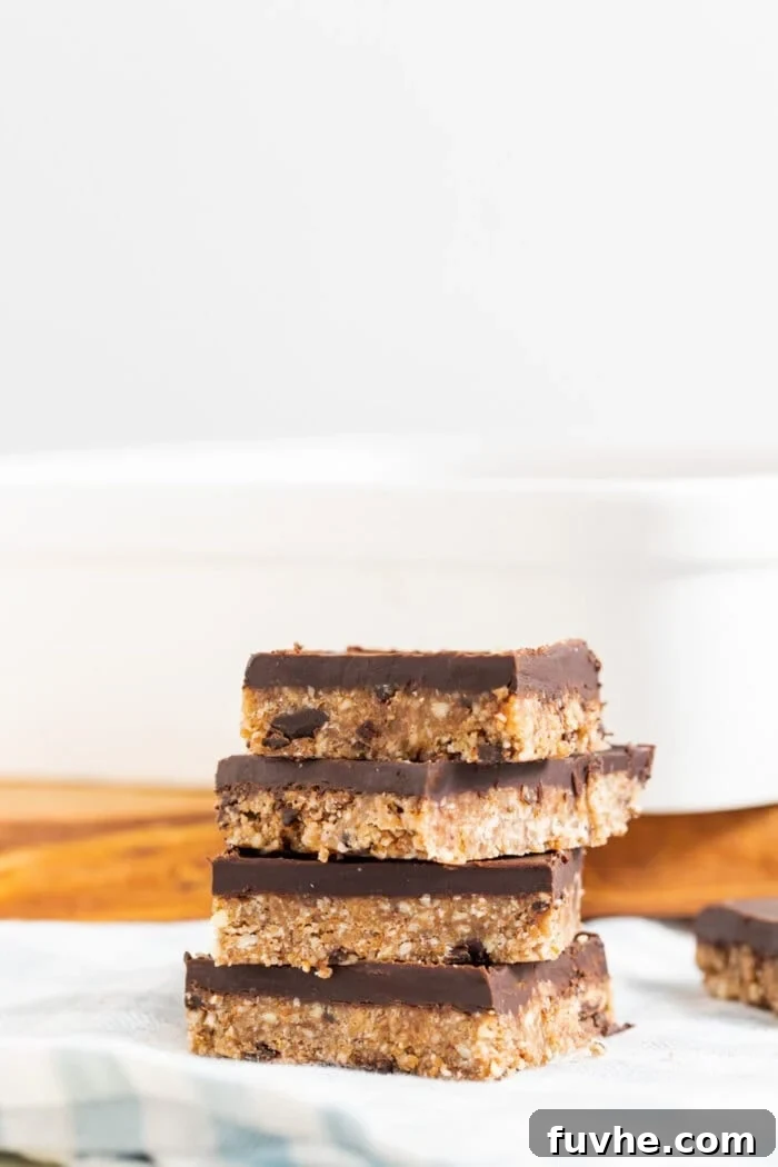 A stack of 4 almond coconut bars topped with chocolate.