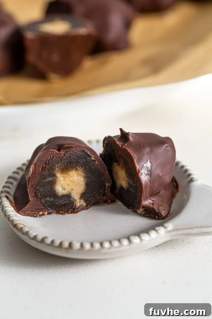 Cut open chocolate-covered medjool date with a peanut butter filling on a small plate.