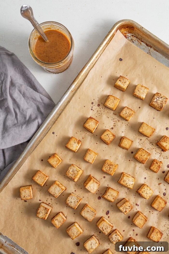 Cubed, baked tofu on a baking tray lined with parchment paper.