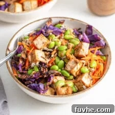 Colourful bowl of rice, tofu, edamame, cabbage and grated carrot.