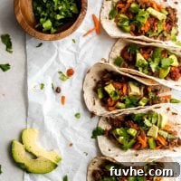 5 lentil tacos lined up on a piece of parchment paper.