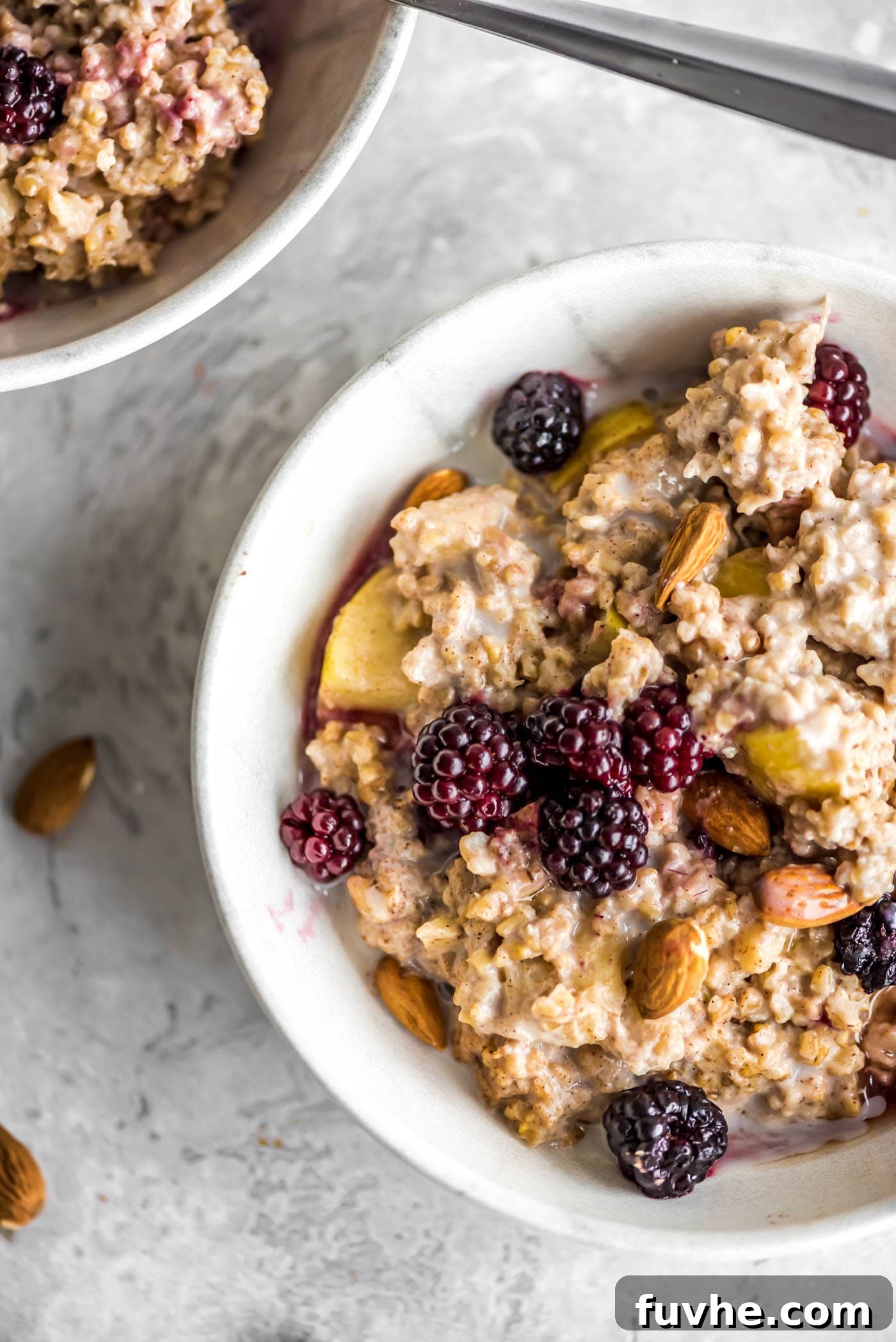 Oven baked steel cut oatmeal with apples and banana, topped with berries and almonds. A healthy and delicious breakfast option.
