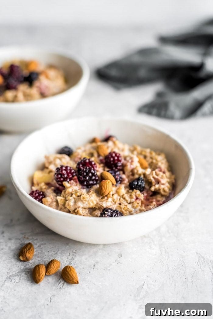 Hot oven baked steel cut oats in two small bowls with blackberries and almonds, perfect for a cozy breakfast.