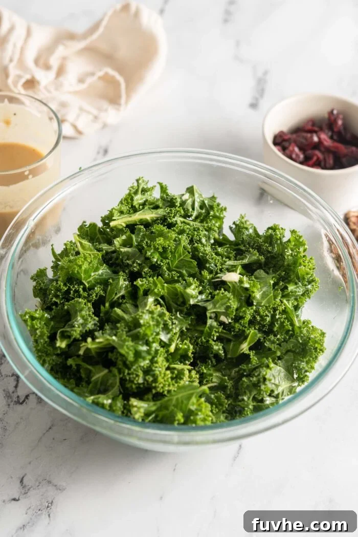 Vibrant Chickpea Garden Salad 4 Large glass bowl with chopped kale tossed with minced garlic, ready for massaging.