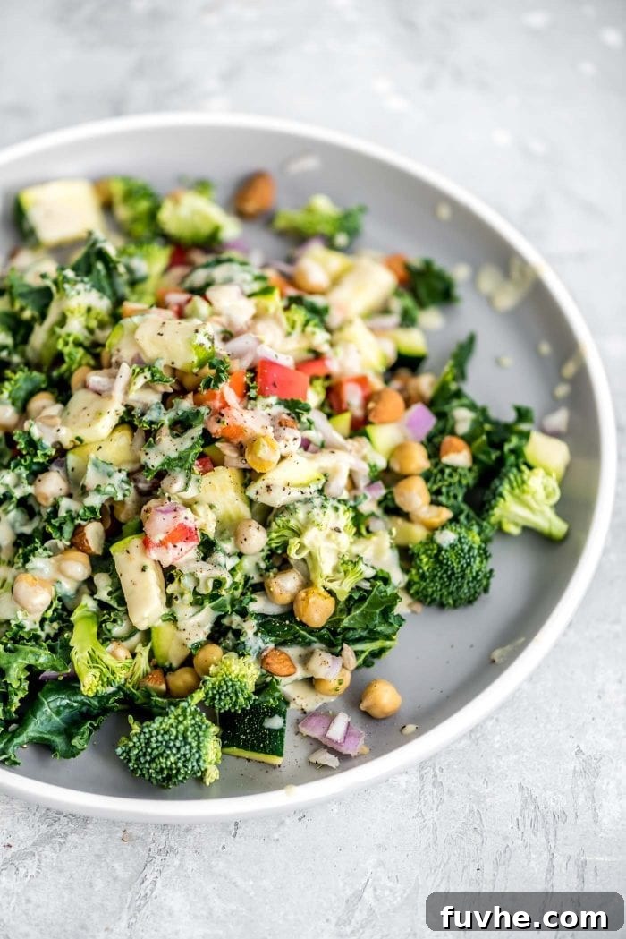 Vibrant Chickpea Garden Salad 8 A close-up of chickpea veggie salad on a plate, featuring almonds, sunflower seeds, bell pepper, kale, and broccoli, beautifully topped with a generous drizzle of lemon tahini dressing.
