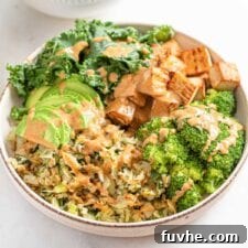 A fresh and colorful low-carb vegan dinner bowl with tofu, cabbage, kale, broccoli, avocado, and a rich sauce.