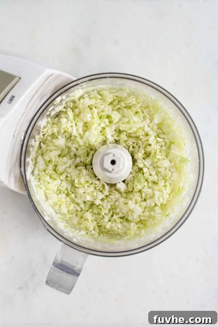 Wholesome Vegan Carb-Conscious Bowls 7 Finely chopped green cabbage within a food processor bowl, demonstrating the 'riced' consistency.