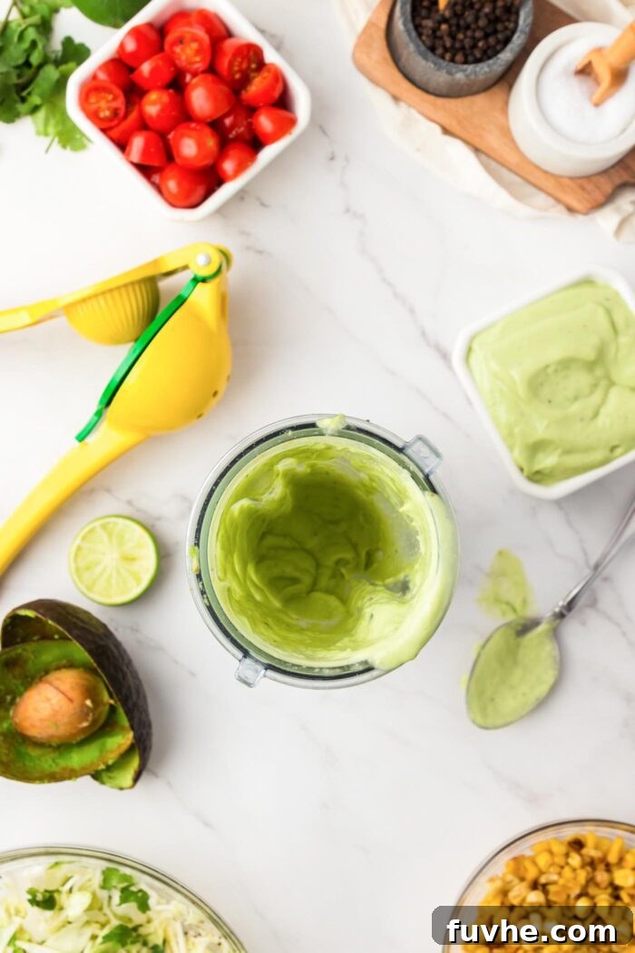 Ingredients for the avocado ranch dressing in a small blender cup, beside a bowl of finished dressing and a citrus press.
