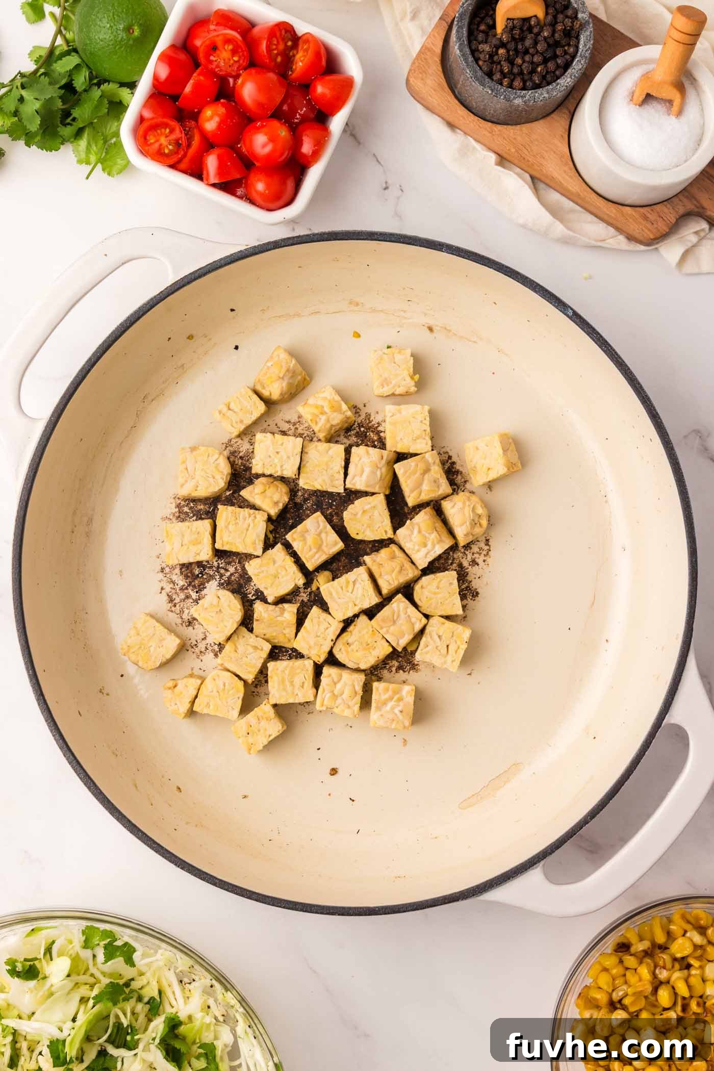 Cubes of tempeh cooking and browning in a hot pan, preparing to be glazed.