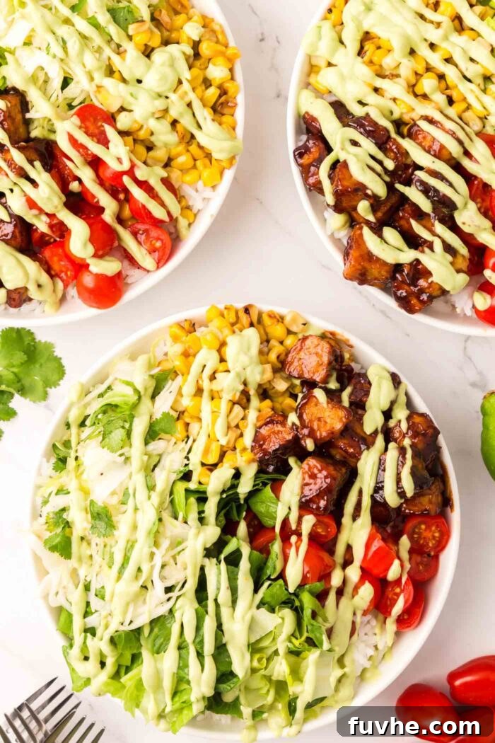 An overhead shot of three fully assembled BBQ tempeh bowls, garnished with fresh cilantro and ready to be enjoyed.