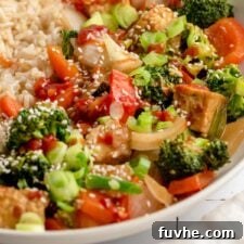 Golden Tempeh Wok Medley 9 Close up of a cube of browned, crispy tempeh in a bowl of vegetable tempeh stir fry with brown rice.
