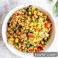 A white bowl filled with vegan basil fried rice with peas and corn.