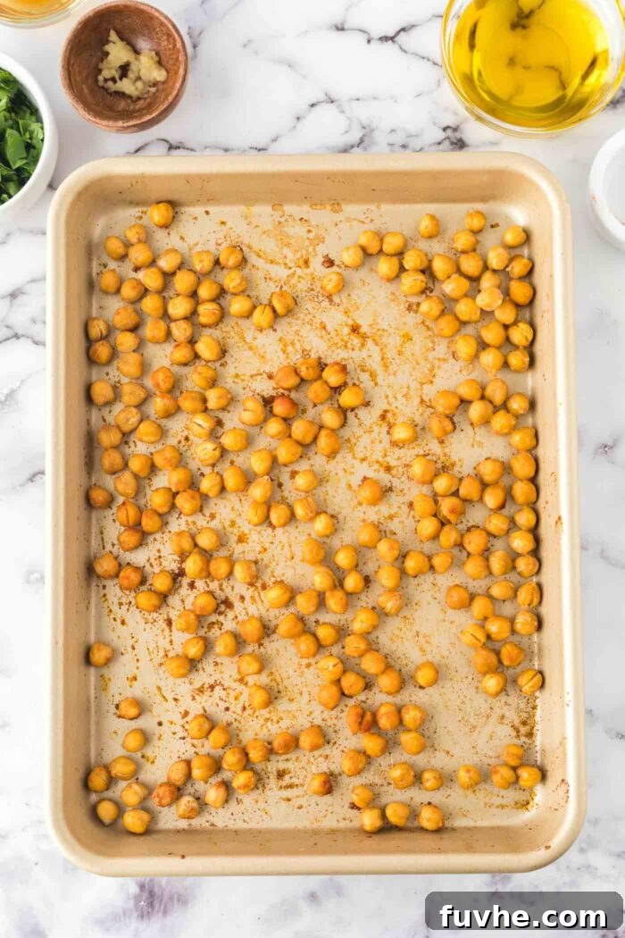 Crispy, spiced chickpeas spread out on a baking pan, roasted until golden brown.