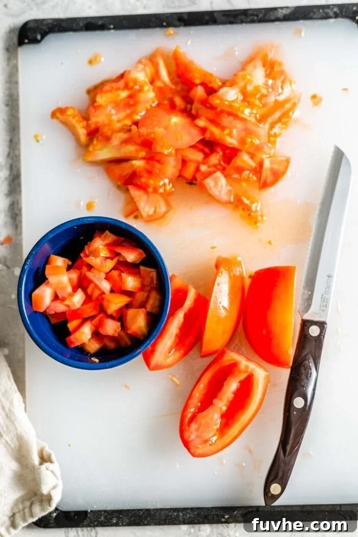 Sliced roma tomato on a cutting board, ready for dicing.