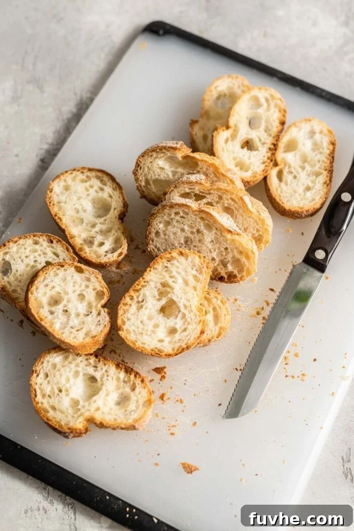 Sliced baguette on a cutting board, prepared for toasting.