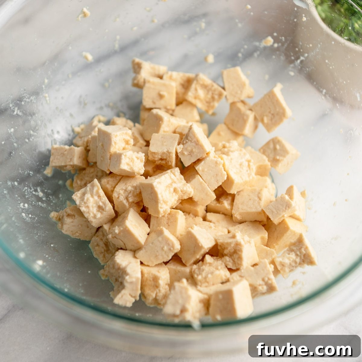 Plant-Based Greek Pasta Salad 4 Chunks of extra firm tofu in a glass mixing bowl.