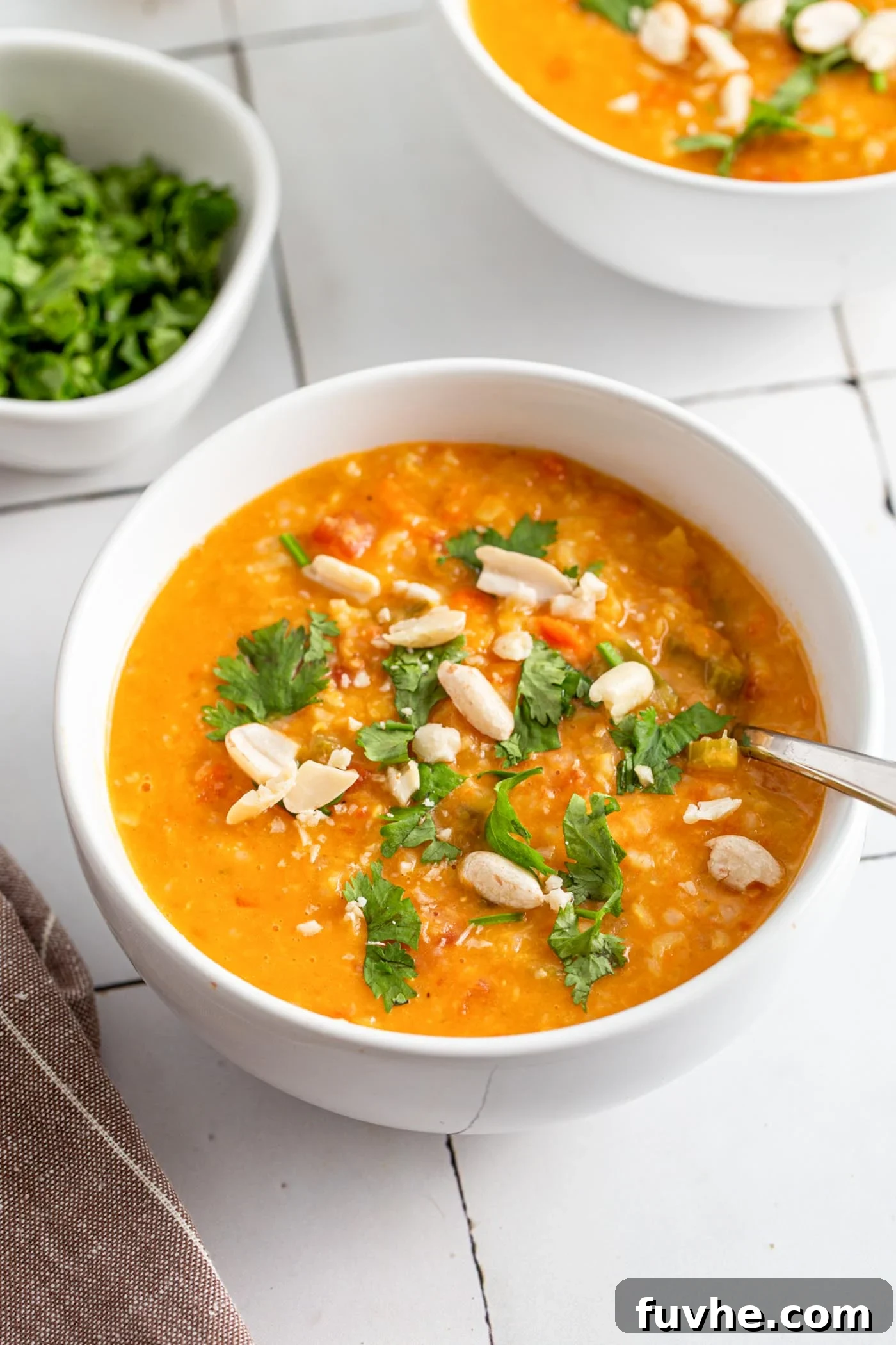 Bowl of vegan mulligatawny soup topped with fresh herbs and peanuts.