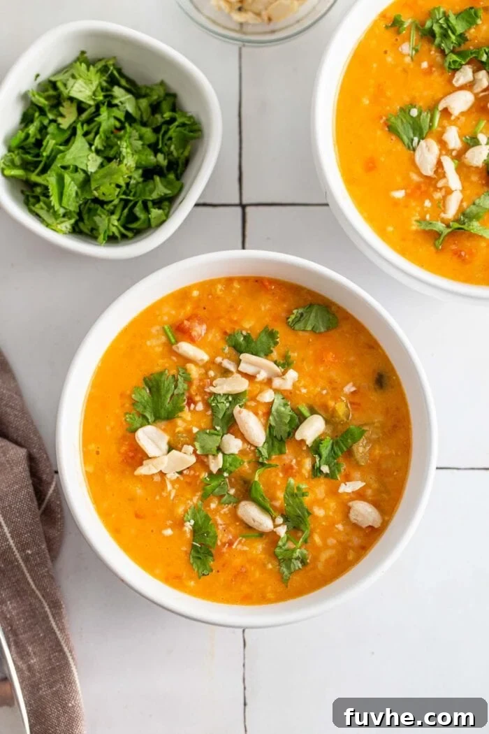 Bowl of mulligatawny soup topped with fresh herbs and peanuts, ready to be served.