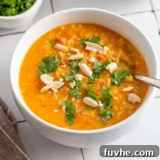 Bowl of mulligatawny soup topped with fresh herbs and peanuts.