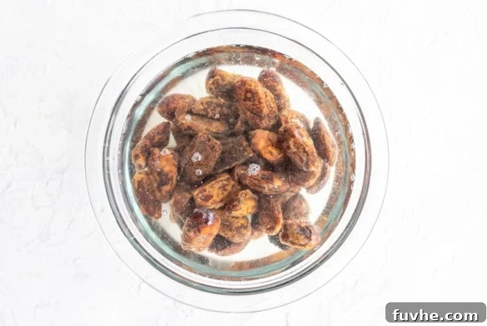 Pitted dates soaking in hot water in a small glass bowl, ready to be softened for the brownie batter.