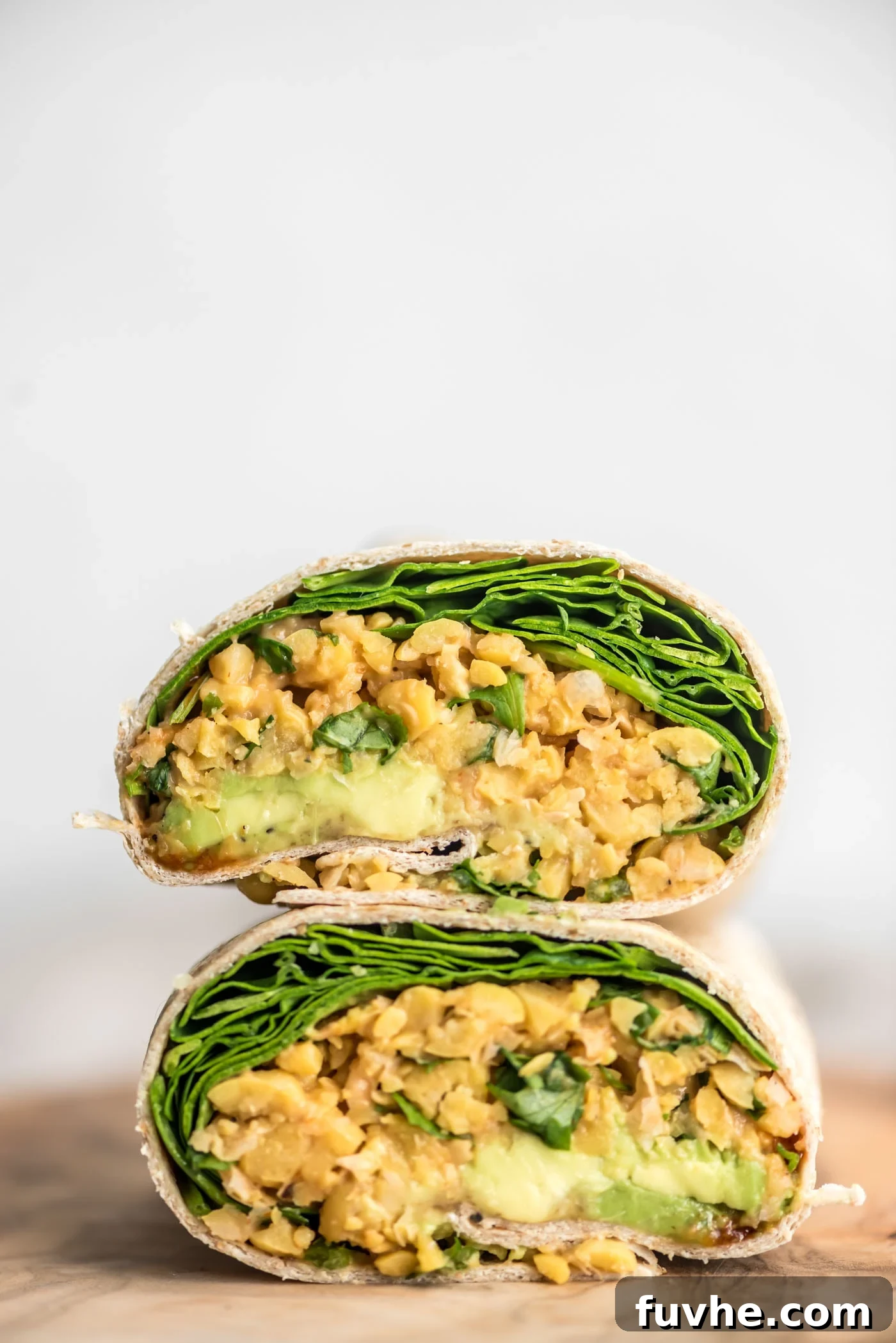 Kickin' Chickpea Avocado Wraps 2 Two halves of a wrap stuffed with spicy chickpeas, creamy avocado, and fresh spinach.