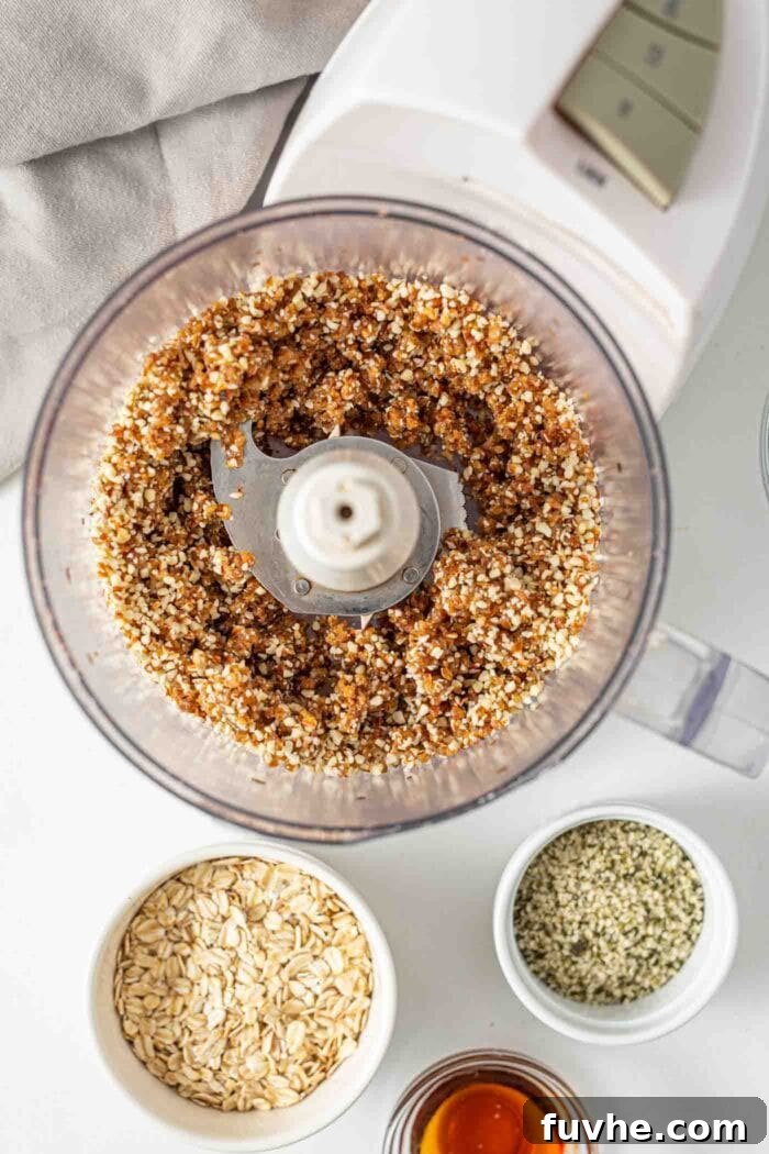 A crumbly blend of almonds and dates processed in a food processor, forming the base for energy bars.