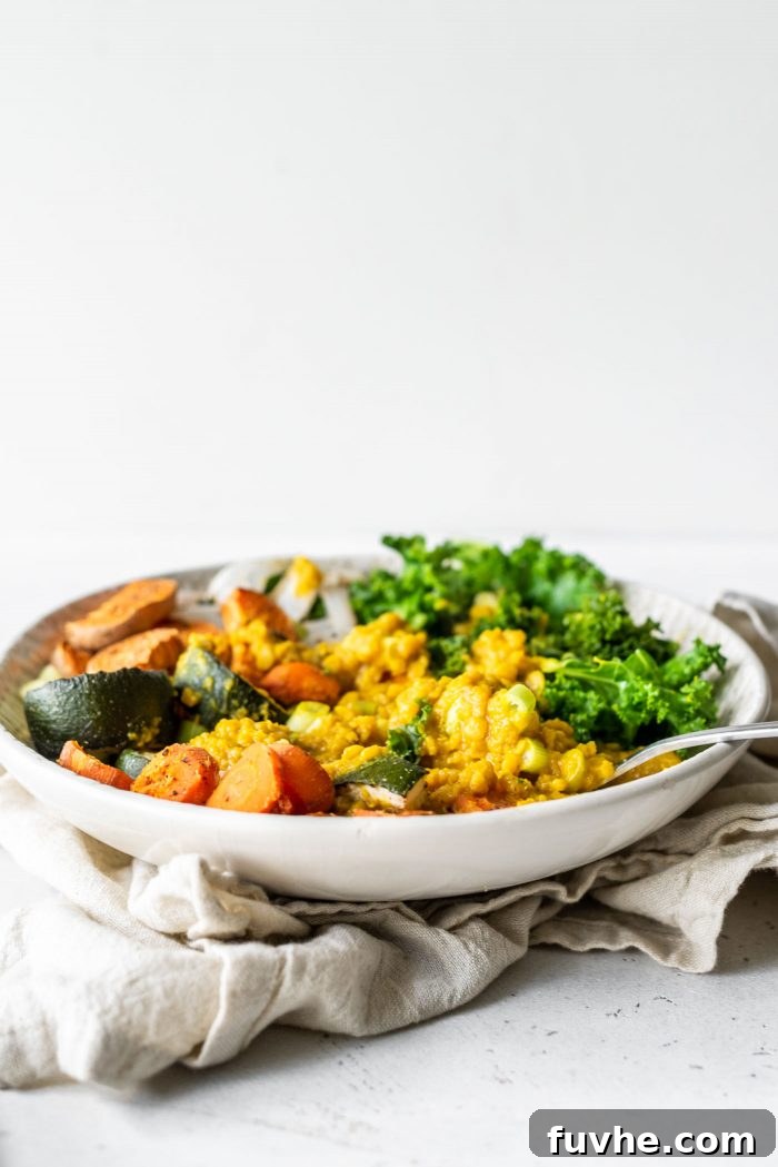 Golden Lentil Curry Bowl 7 Bowl with lentils, roasted vegetables and kale against a white background.