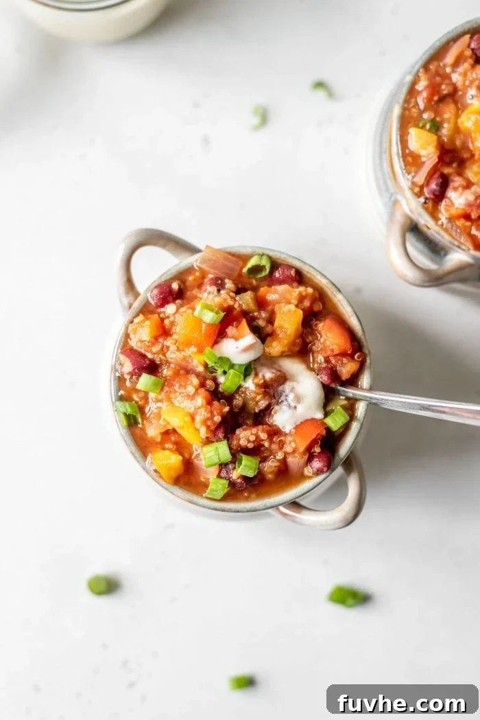 Bowl of vegan chili topped with tofu sour cream and green onions.
