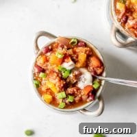 Bowl of vegan chili topped with tofu sour cream and green onions.