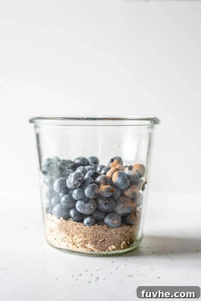 No-Bake Blueberry Muffin Oats 5 Oats, flax, lemon, and blueberries layered in a glass jar, ready to be mixed.